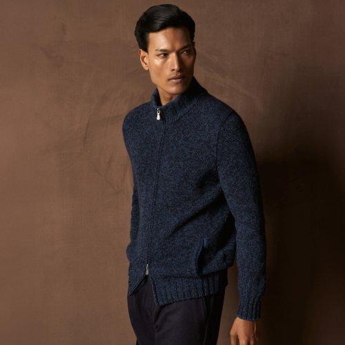 A man wearing a blue zip-up sweater jacket