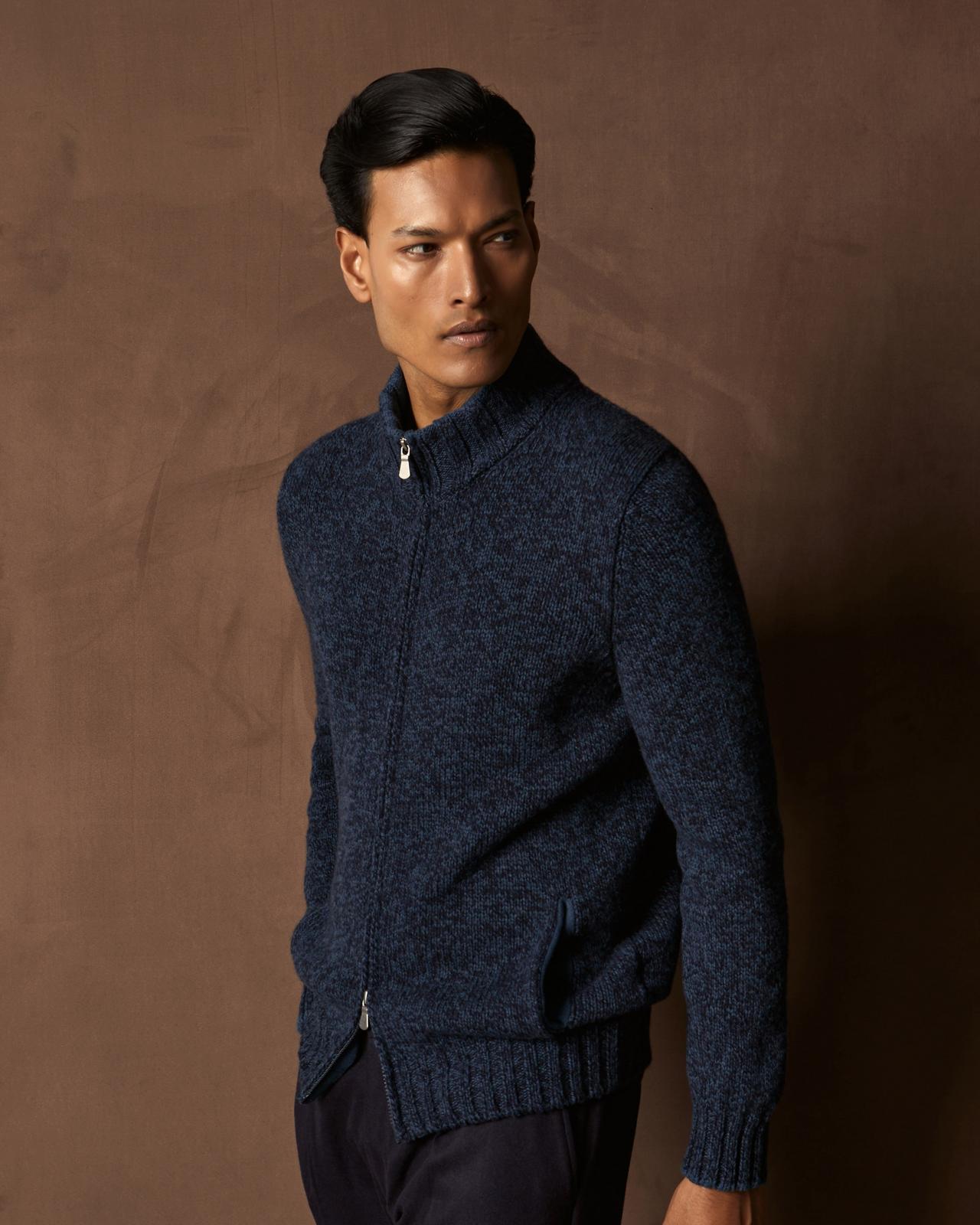 A man wearing a blue zip-up sweater jacket