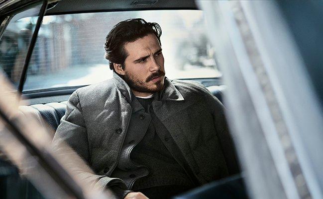 A male model wearing a Moncler jacket layered over a knit