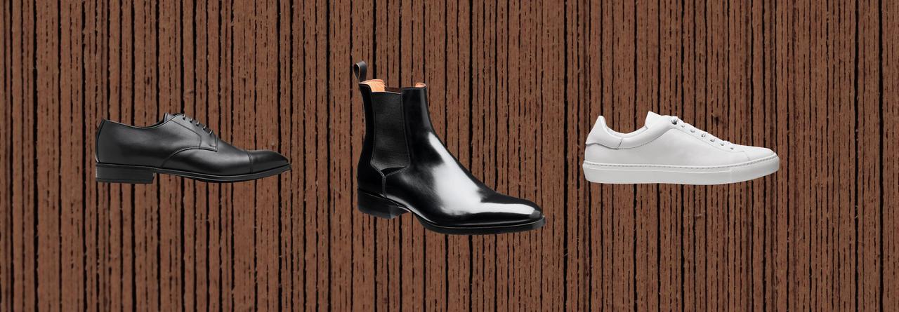 Baskets blanches, chaussures habillées noires et bottes noires sur fond brun.