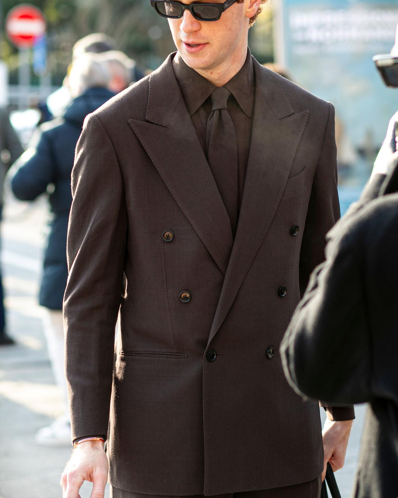 Homme portant un complet croisé brun foncé avec une chemise et une cravate assorties