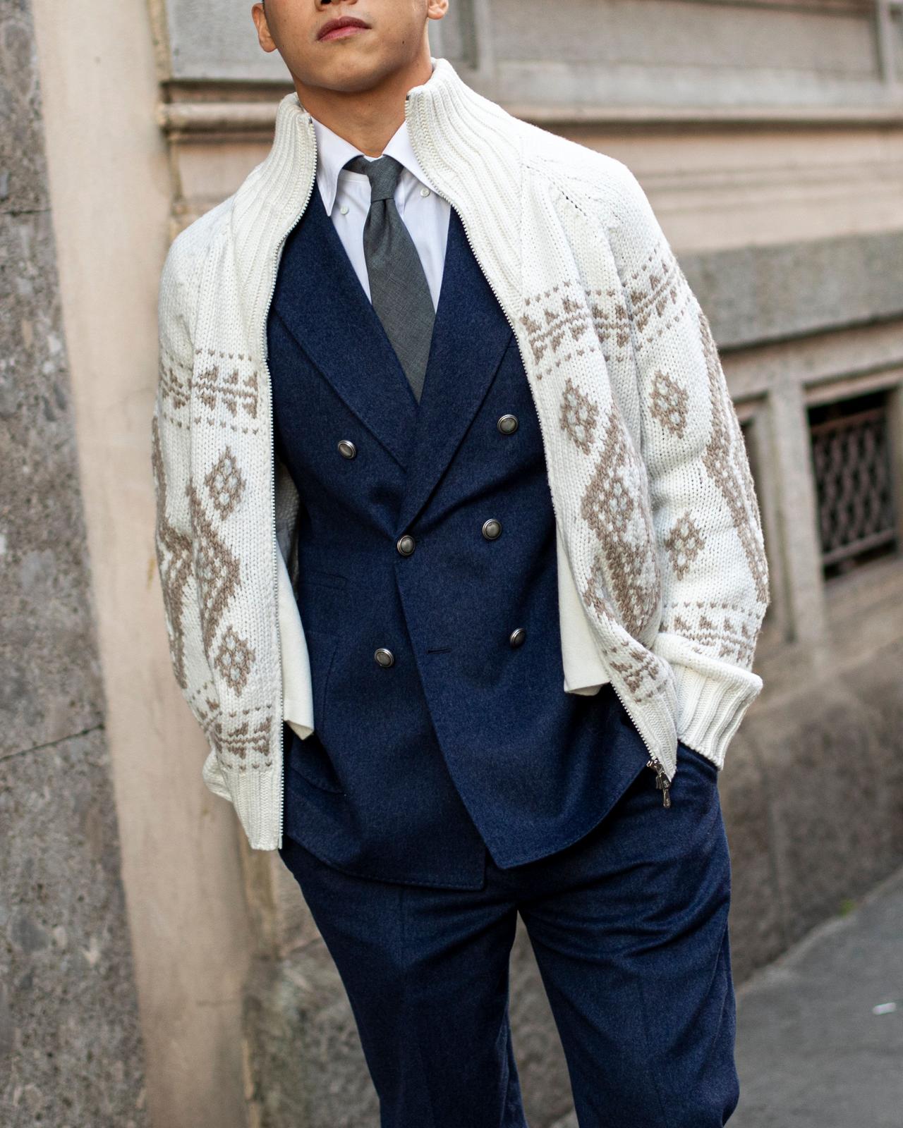 Homme vêtu d’un complet bleu avec une cravate grise, superposé à un cardigan blanc