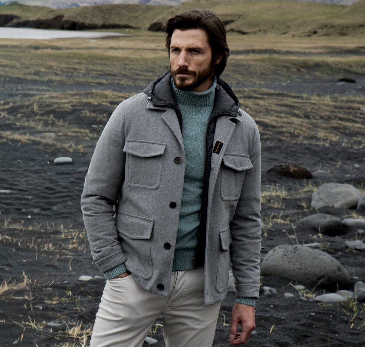 Un mannequin homme portant une veste grise à grandes poches, assortie d’un chandail à col roulé vert et d’un pantalon gris