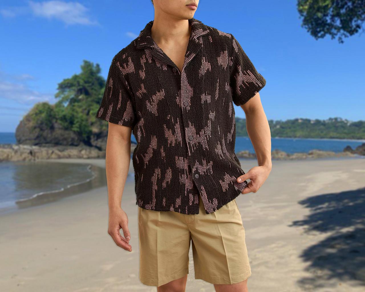 A model wearing printed t-shirt and a tan shorts standing at a beach