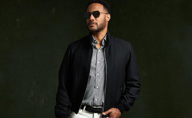 A male model wearing a black jacket layered over a striped shirt