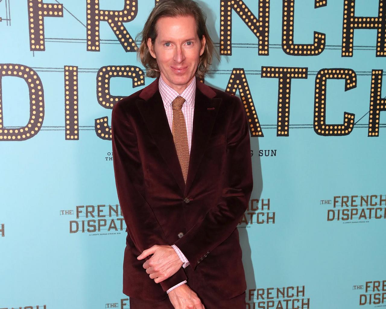 Wes Anderson portant un complet en velours bordeaux avec une cravate à motifs à la première de The French Dispatch