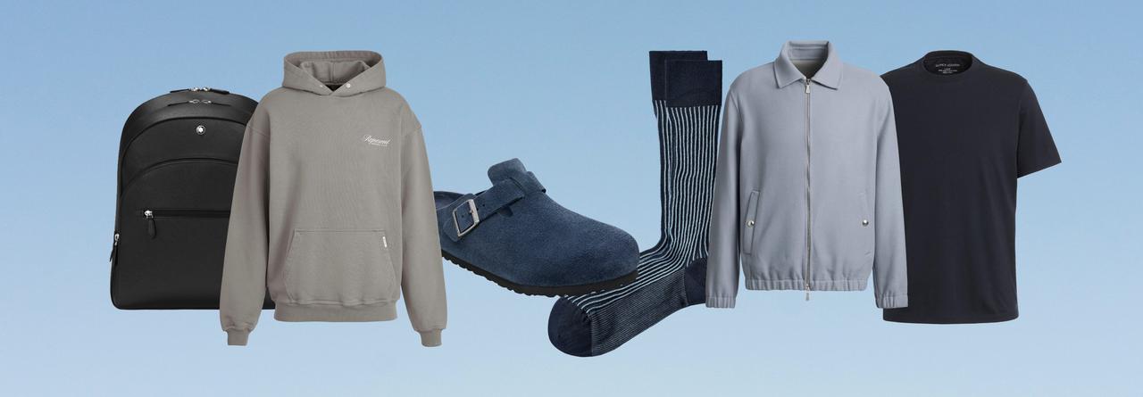 Agencement d’essentiels de voyage comprenant un sac à dos, un hoodie, des bas, une chemise et un t-shirt sur un fond bleu