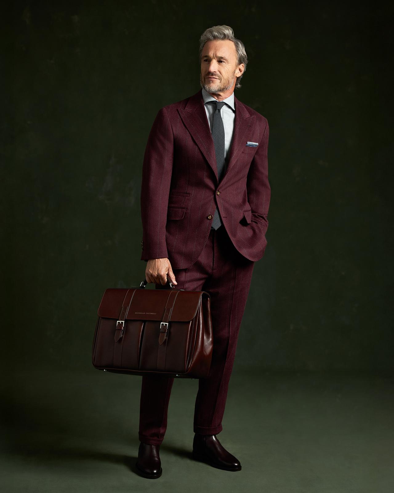 Un mannequin masculin portant un complet Brunello Cuccinelli, tenant une mallette à la main