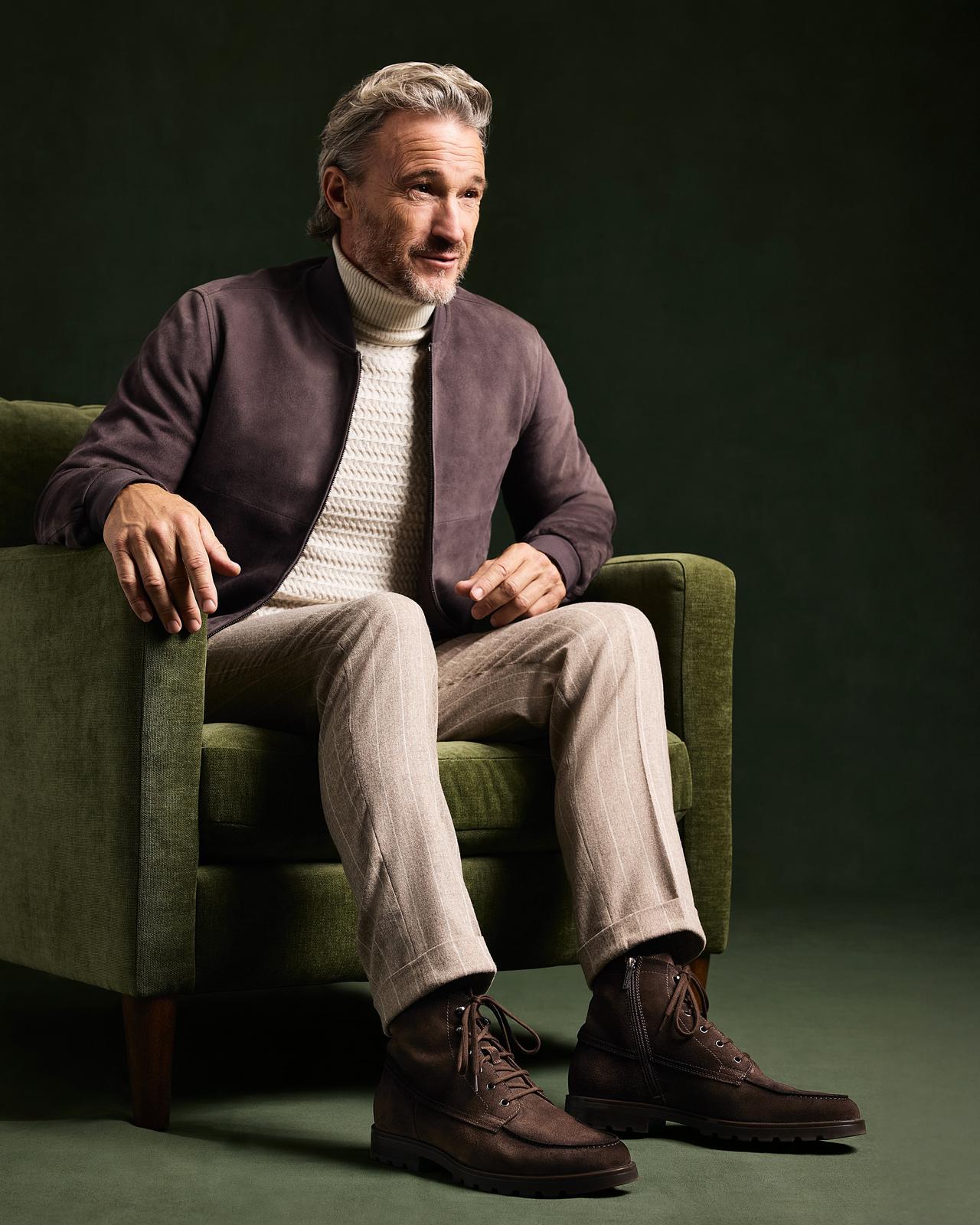 Male model sitting in a chair wearing Santoni lace up boots