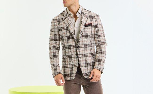 Un homme portant un veston sport à carreaux beige superposé à une chemise pâle
