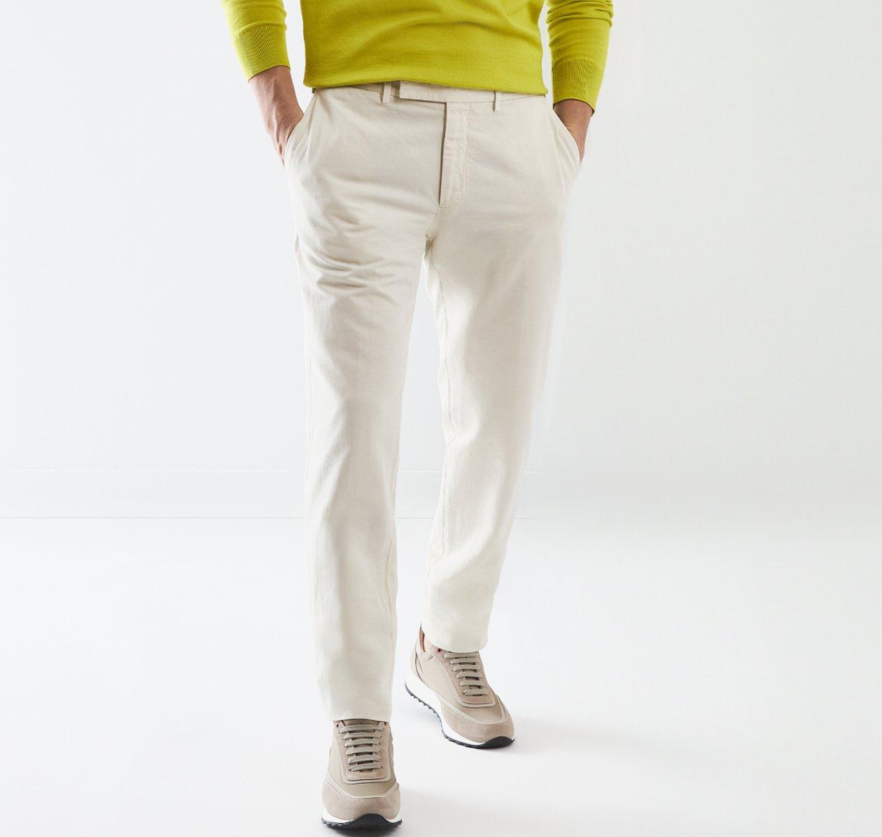 A man wearing off-white pants paired with a lime green sweater and beige sneakers