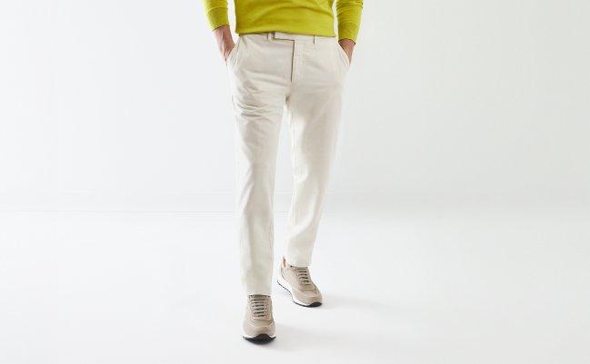 A man wearing off-white pants paired with a lime green sweater and beige sneakers
