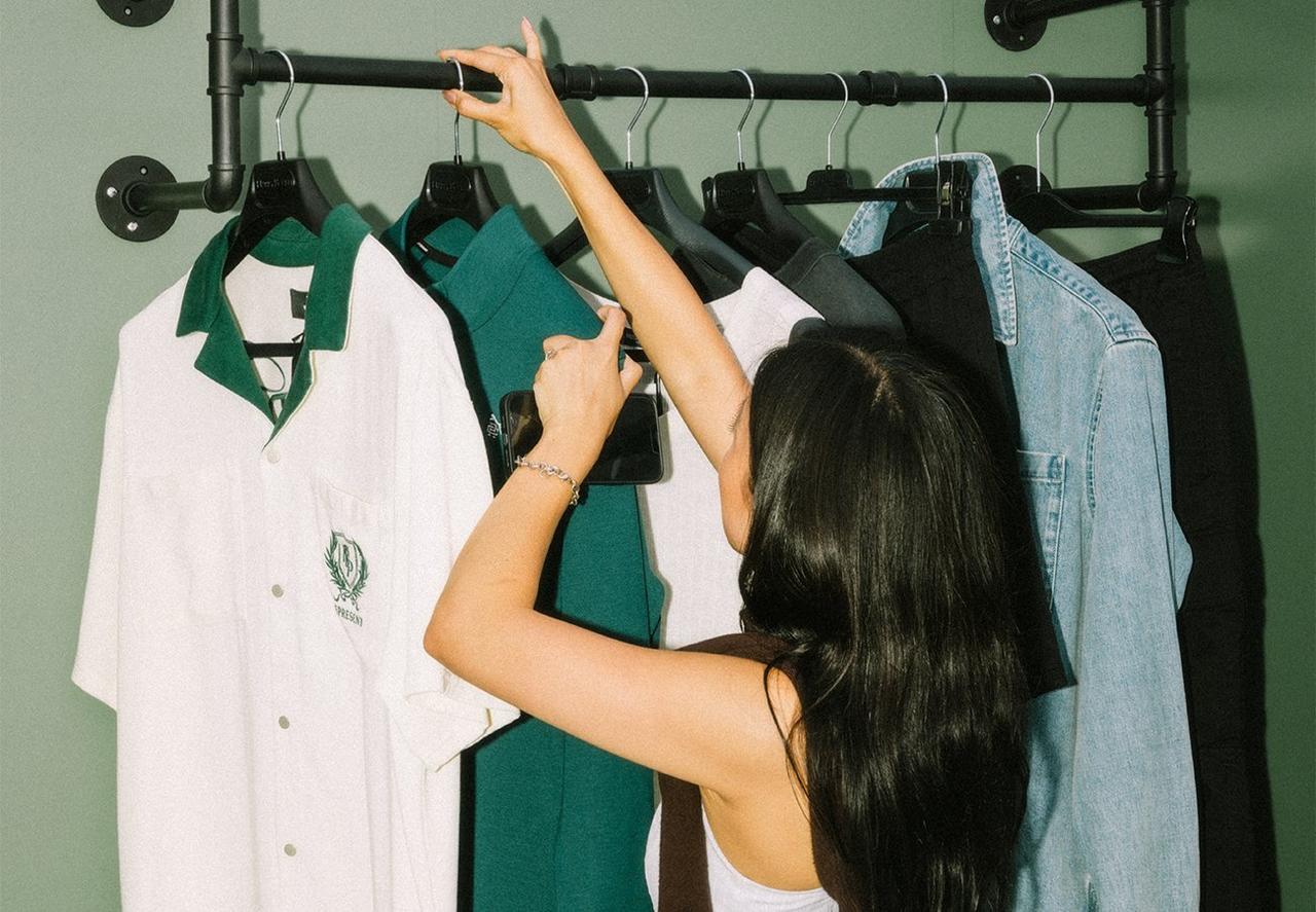 Une femme regardant des vêtements pour hommes sur un portant