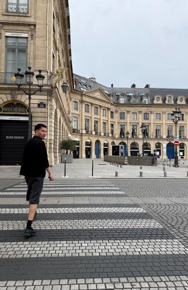 Acheteur traversant un pavement à motifs devant le Palais-Royal à Paris
