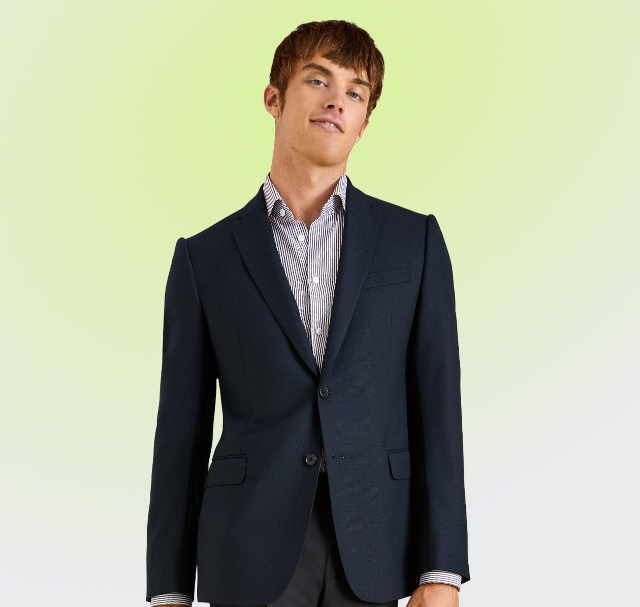 A man wearing a tailored navy blue blazer paired with a light blue and white striped dress shirt