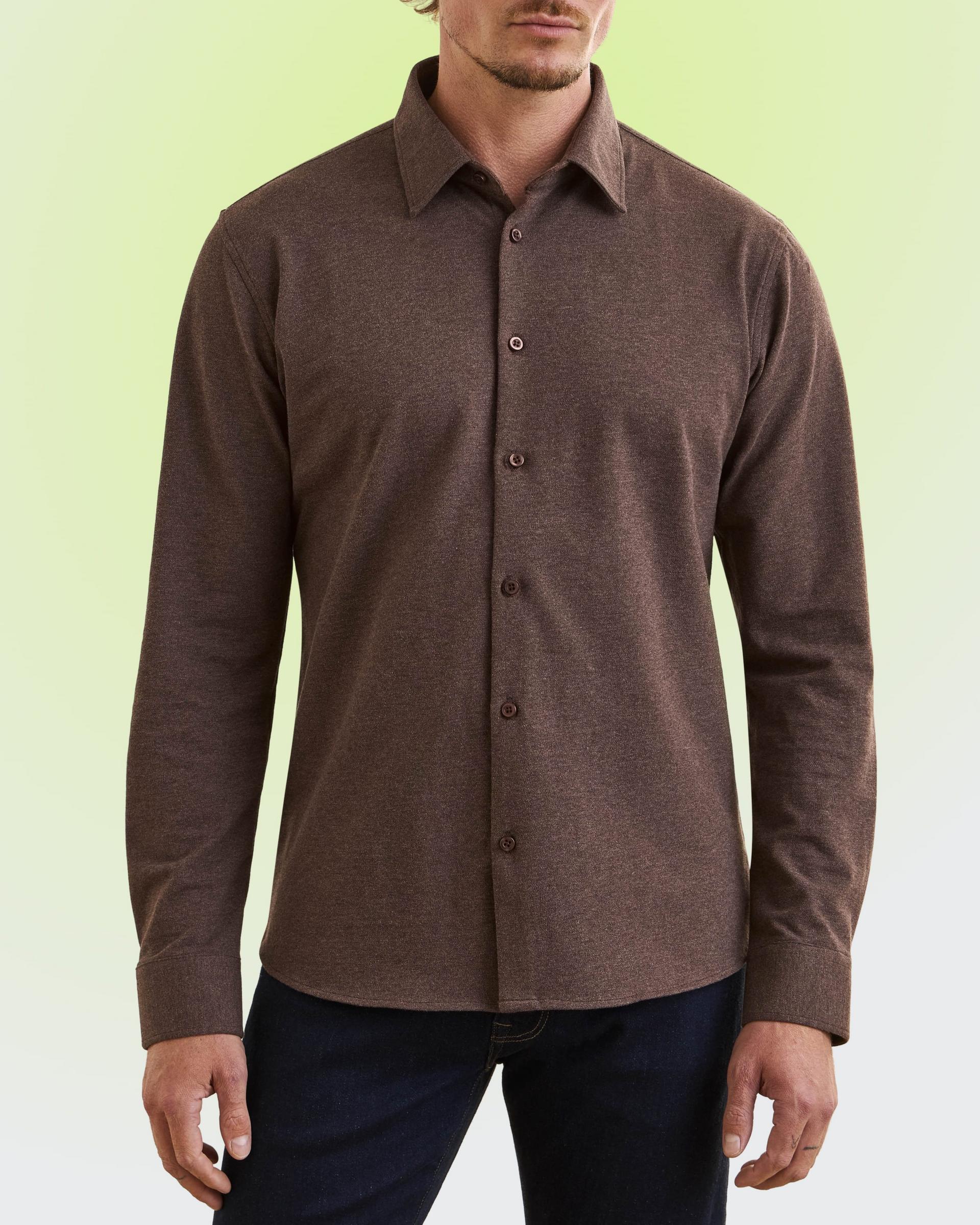 Homme portant une chemise brune à manches longues boutonnée et un pantalon bleu marine foncé.