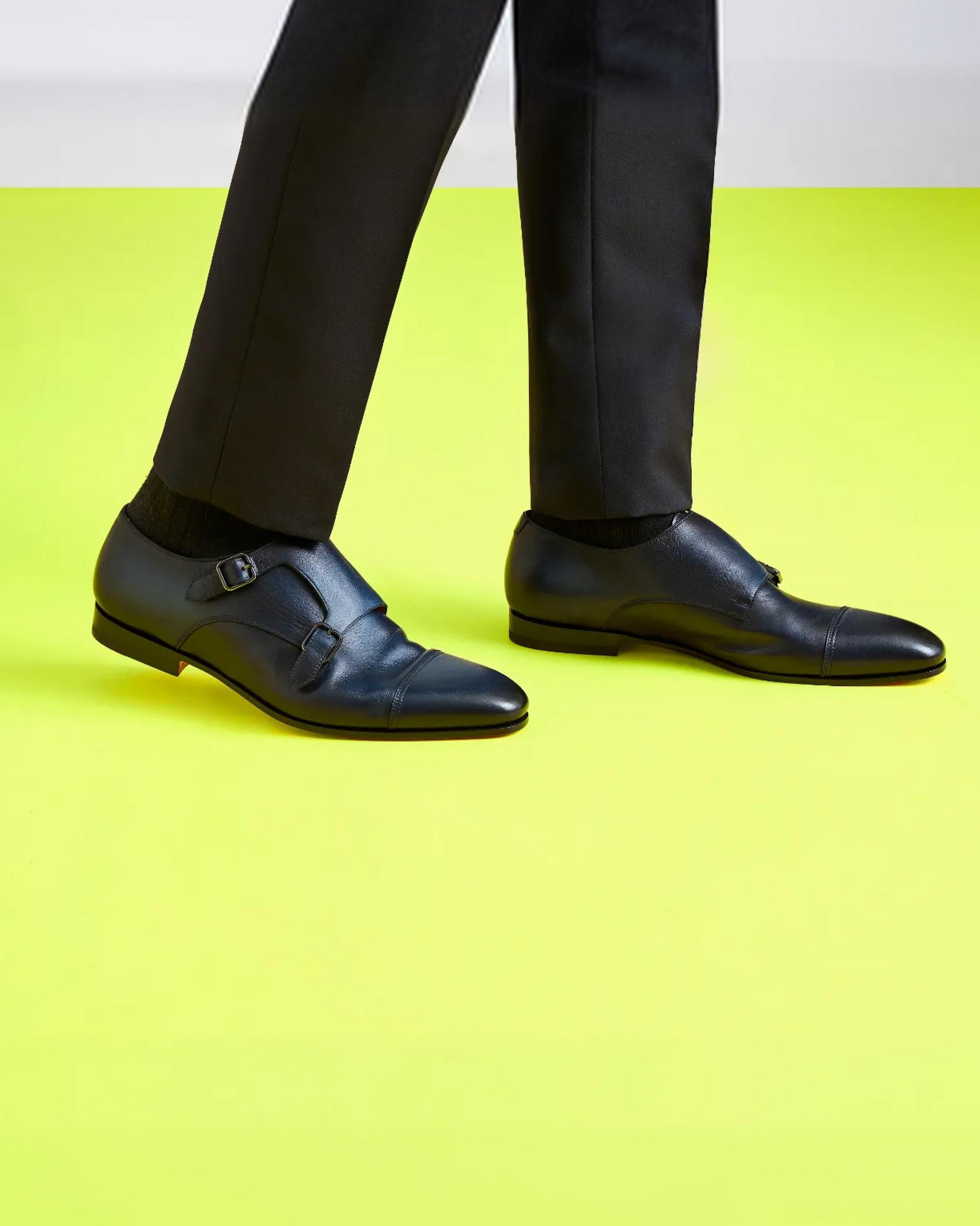 Man wearing black trousers and black leather double monk strap shoes