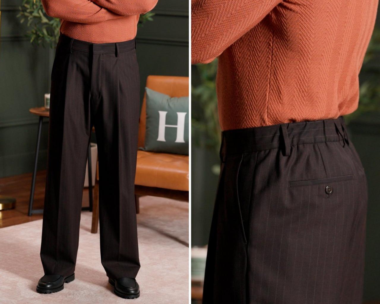 a person wearing black wide-leg trousers paired with a textured orange sweater, standing in a modern living room setting