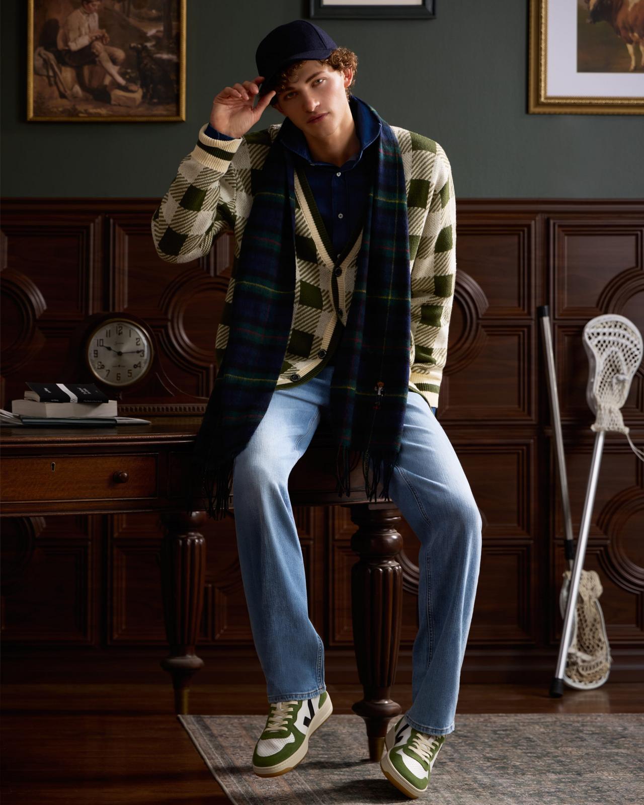 model wearing a plaid cardigan, blue jeans, and green-and-white sneakers
