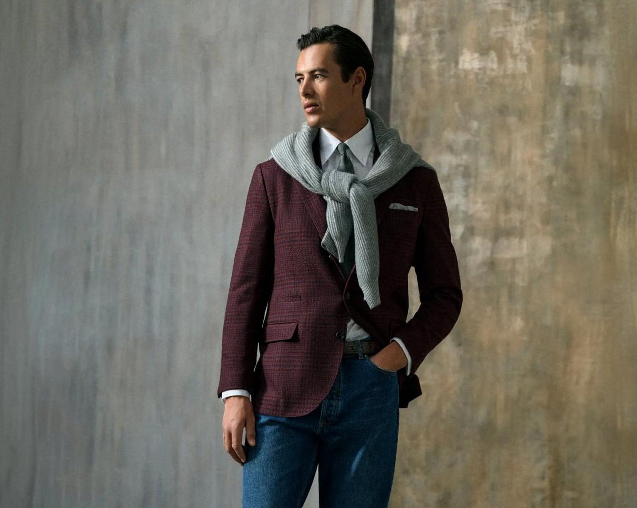 model dressed in a burgundy checkered blazer, white dress shirt, and a light gray scarf, paired with blue jeans