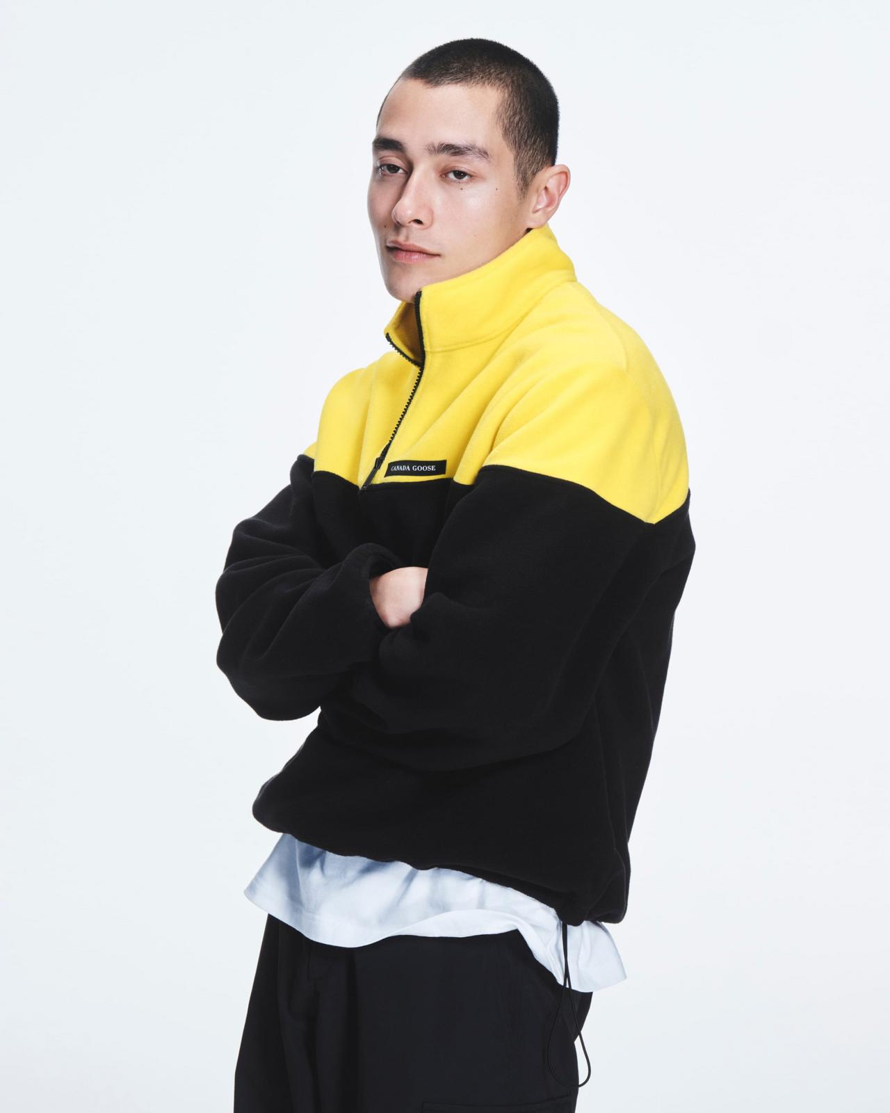 Homme portant un pull demi-zip en polaire à blocs de couleurs jaune et noir de Canada Goose, collection A/H26