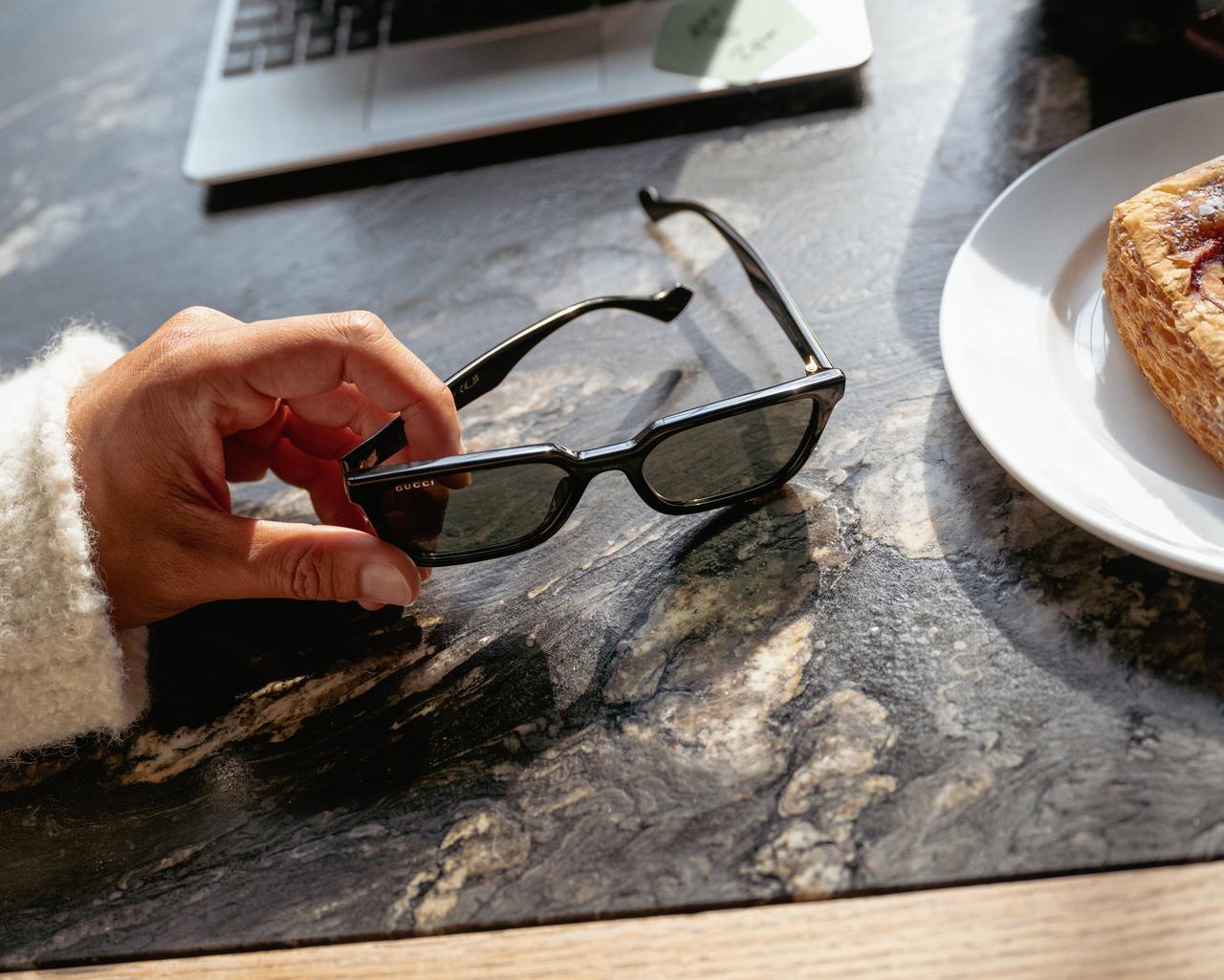 main masculine tenant des lunettes de soleil sur le bureau avec un ordinateur portable et de la nourriture