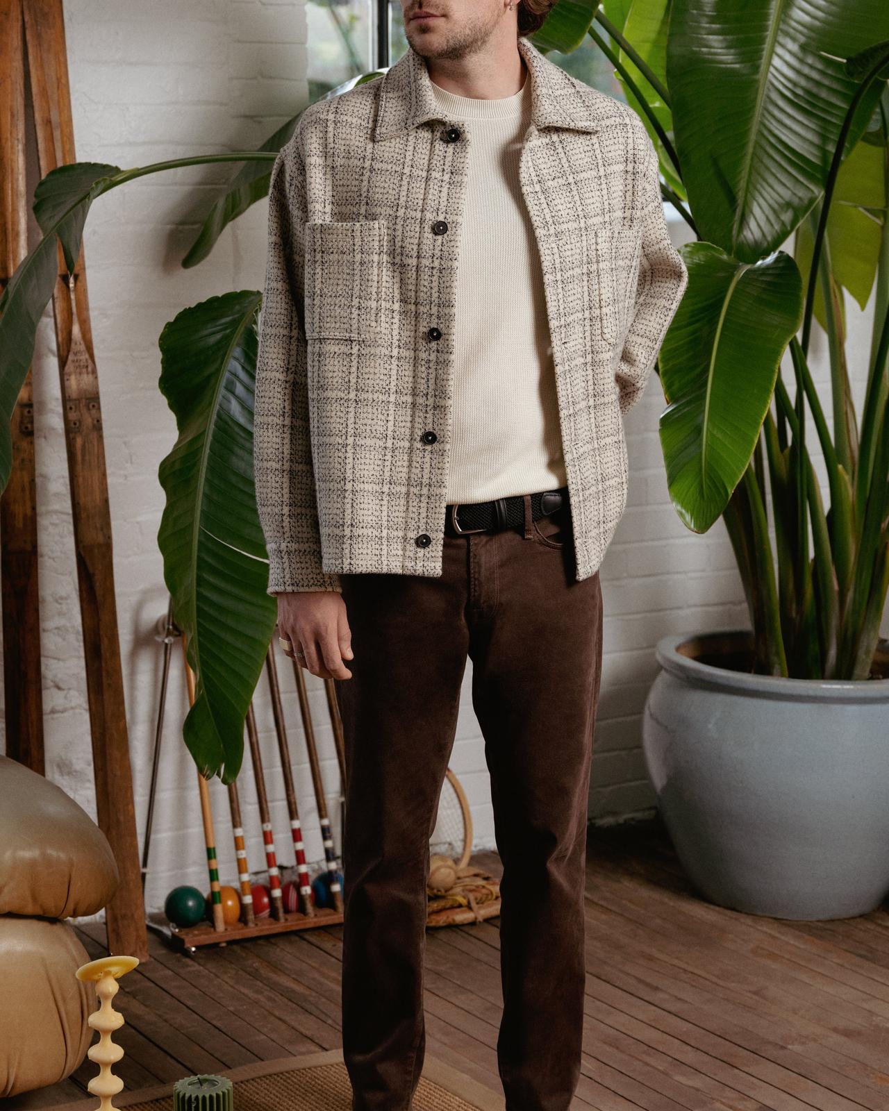 male model wearing overshirt, sweater and coloured jeans posing with one hand in pocket