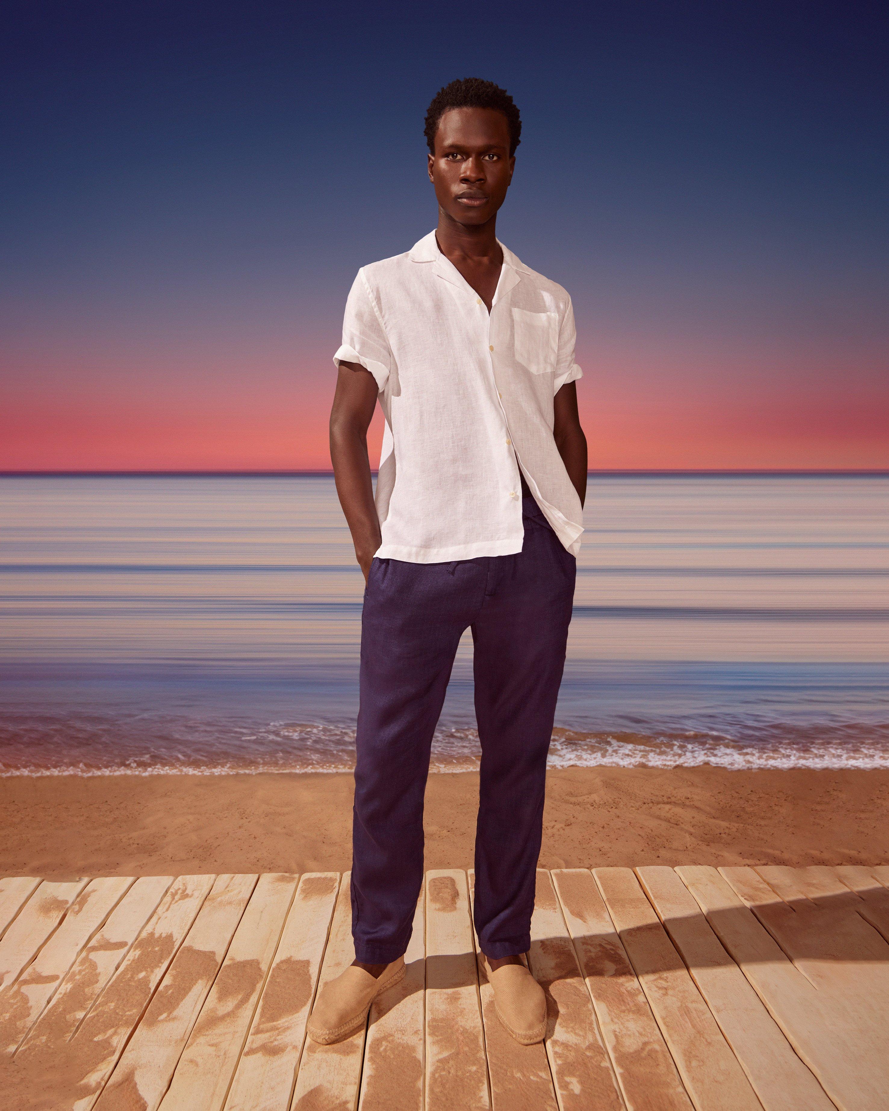 A man standing on a wooden dock with the ocean in the background