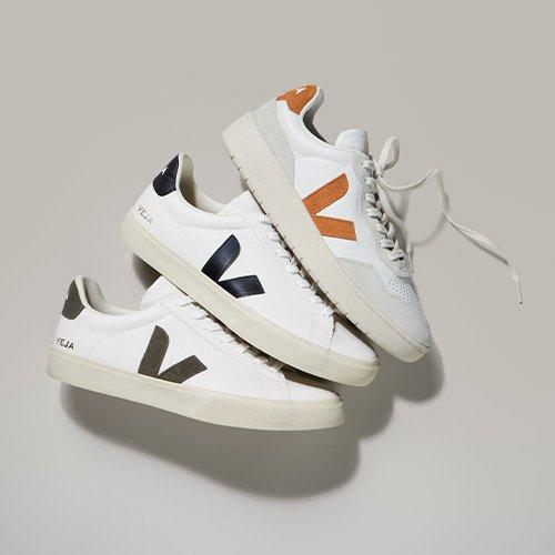 Two white and orange VEJA sneakers with a black and white sole