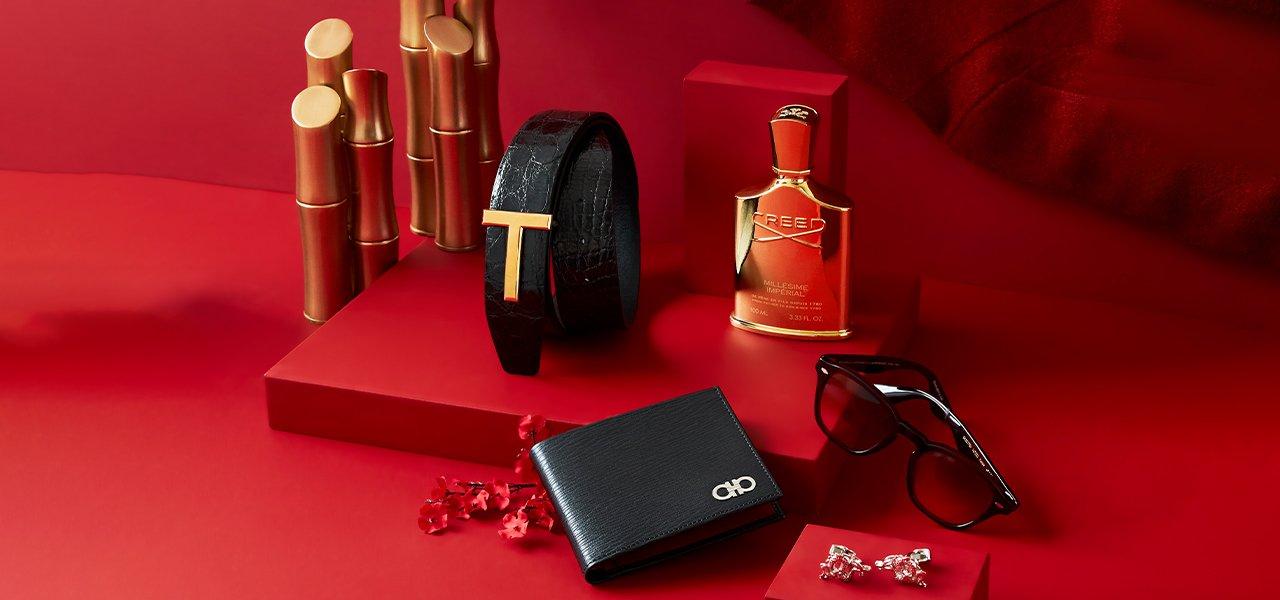 Une table rouge avec un portefeuille, des lunettes de soleil et une bouteille de parfum