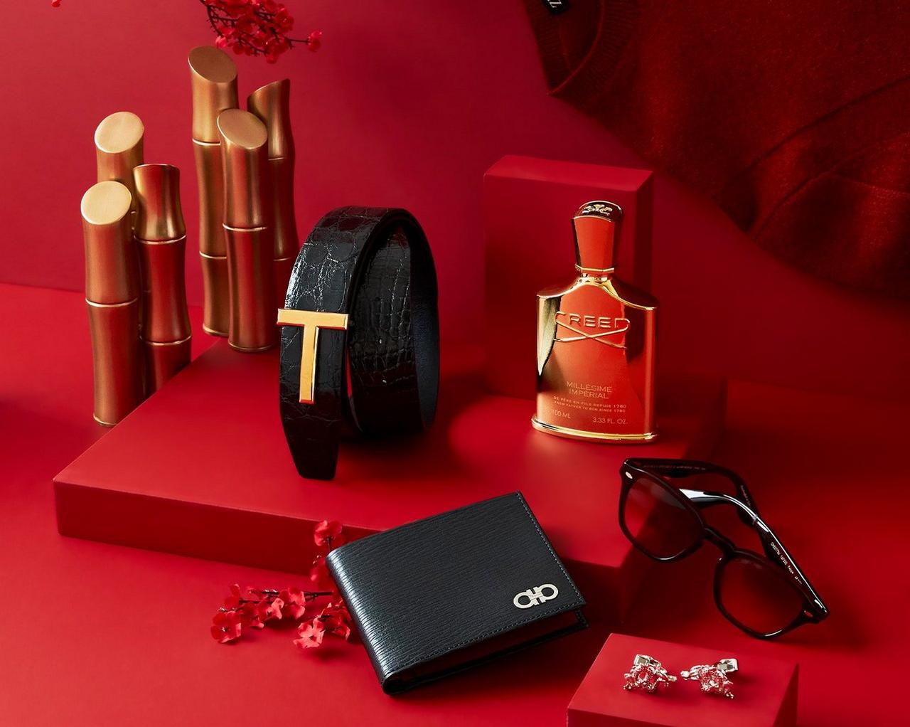 Une table rouge avec un portefeuille, des lunettes de soleil et une bouteille de parfum