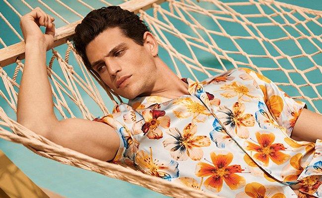 Male model wearing floral patterned resortwear outfit illustrating a beach getaway