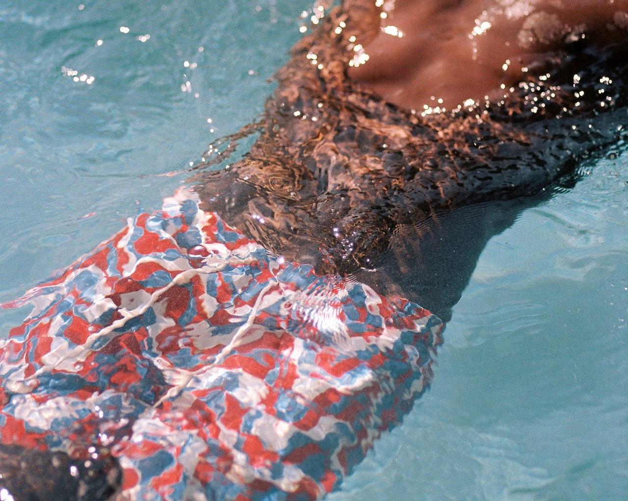 Male model swimming in ocean illustrating new swim and resortwear