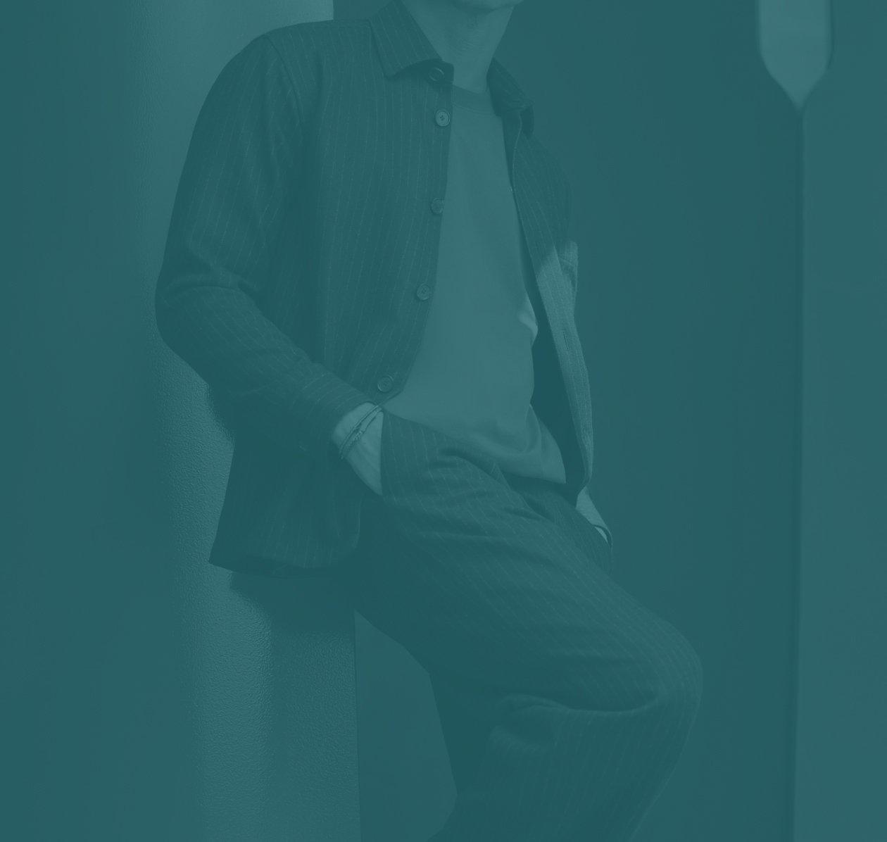 Male model wearing designer outfit against a green backdrop