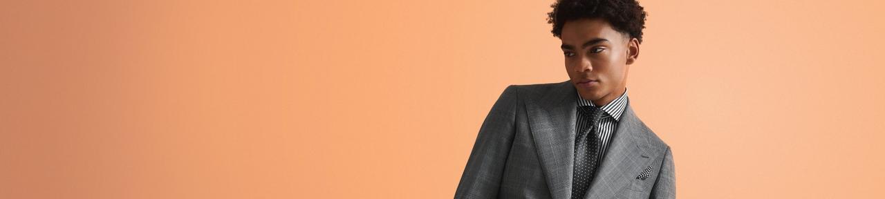 A male model wearing a custom Harold grey tailored suit