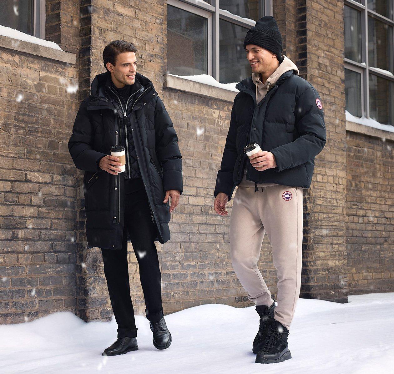 A male model wearing a brown lightweight jacket, paired with a cream colored zip-up knit sweater, white casual shirt, and striped navy tie
