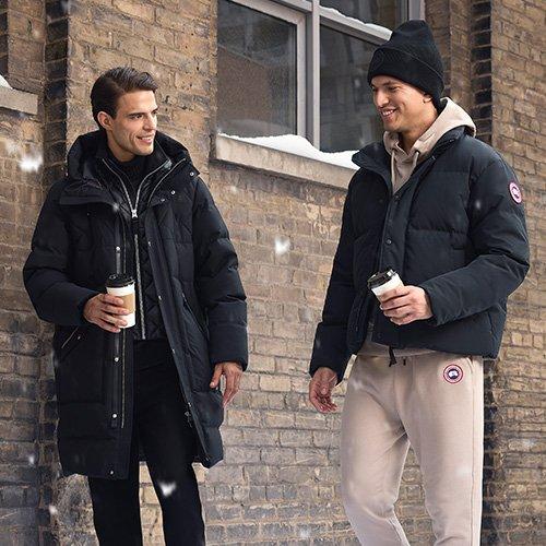 Un mannequin masculin portant une veste en suède gris à col en shearling, agencée avec un chandail beige en tricot à fermeture éclair