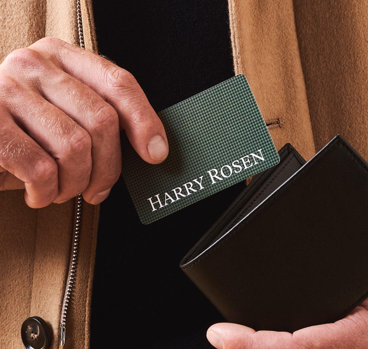 Une main d’homme tenant une carte-cadeau Harry Rosen