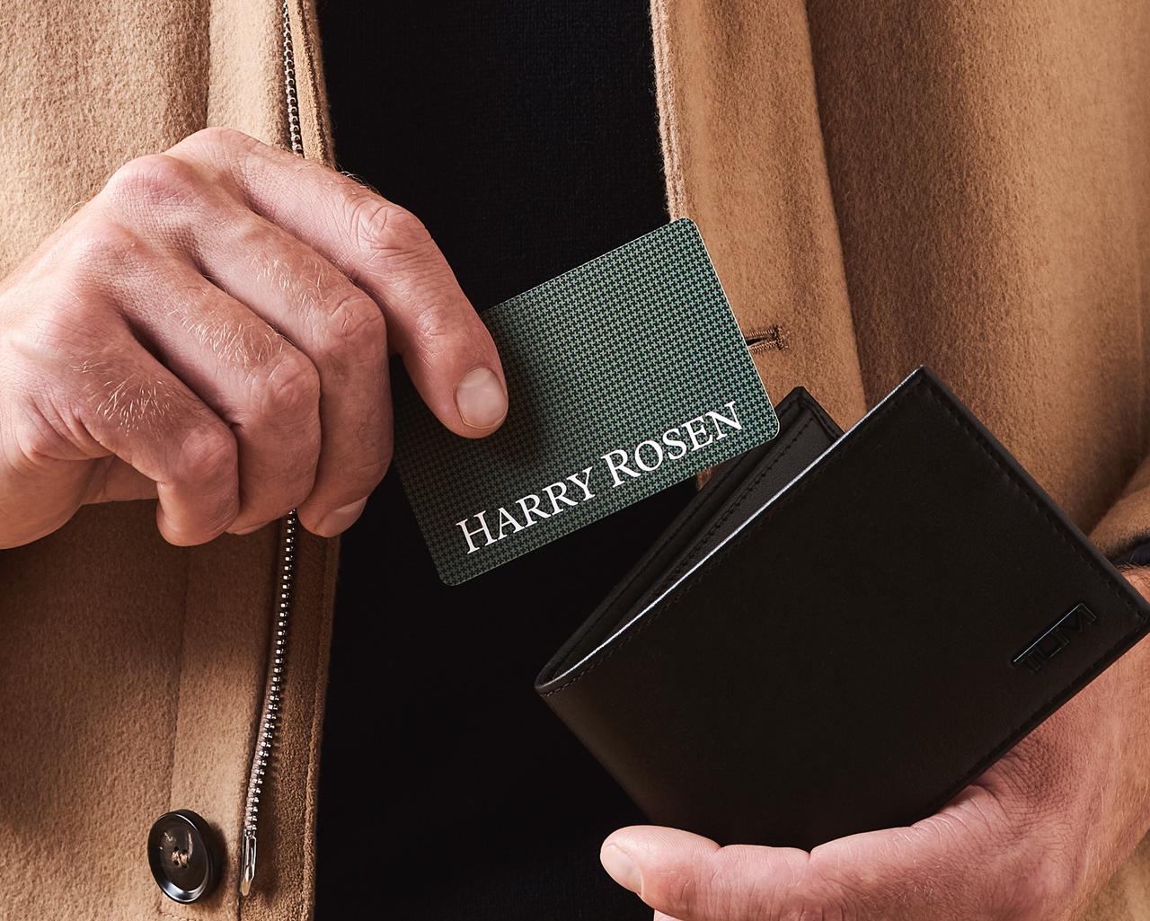 male hands holding gift card and wallet over harry rosen cash desk