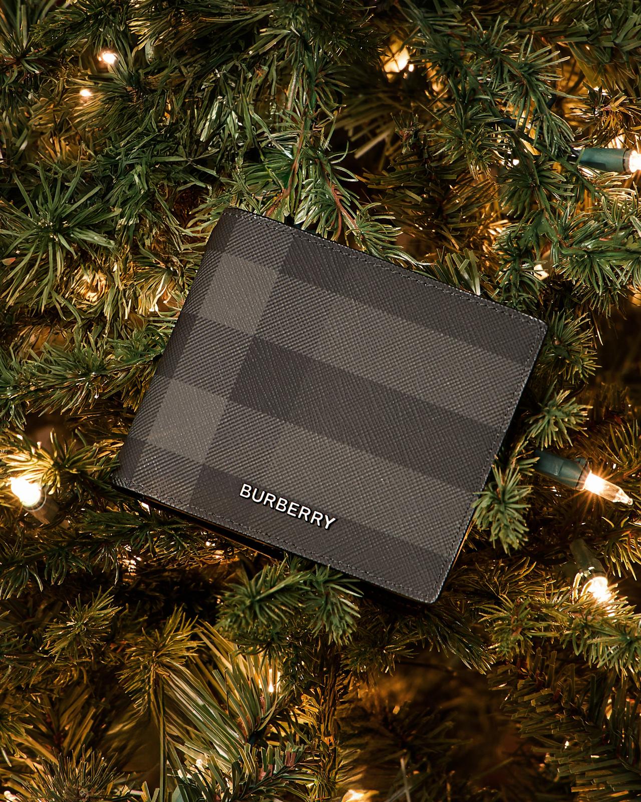 A black and grey wallet hanging from a festive holiday tree