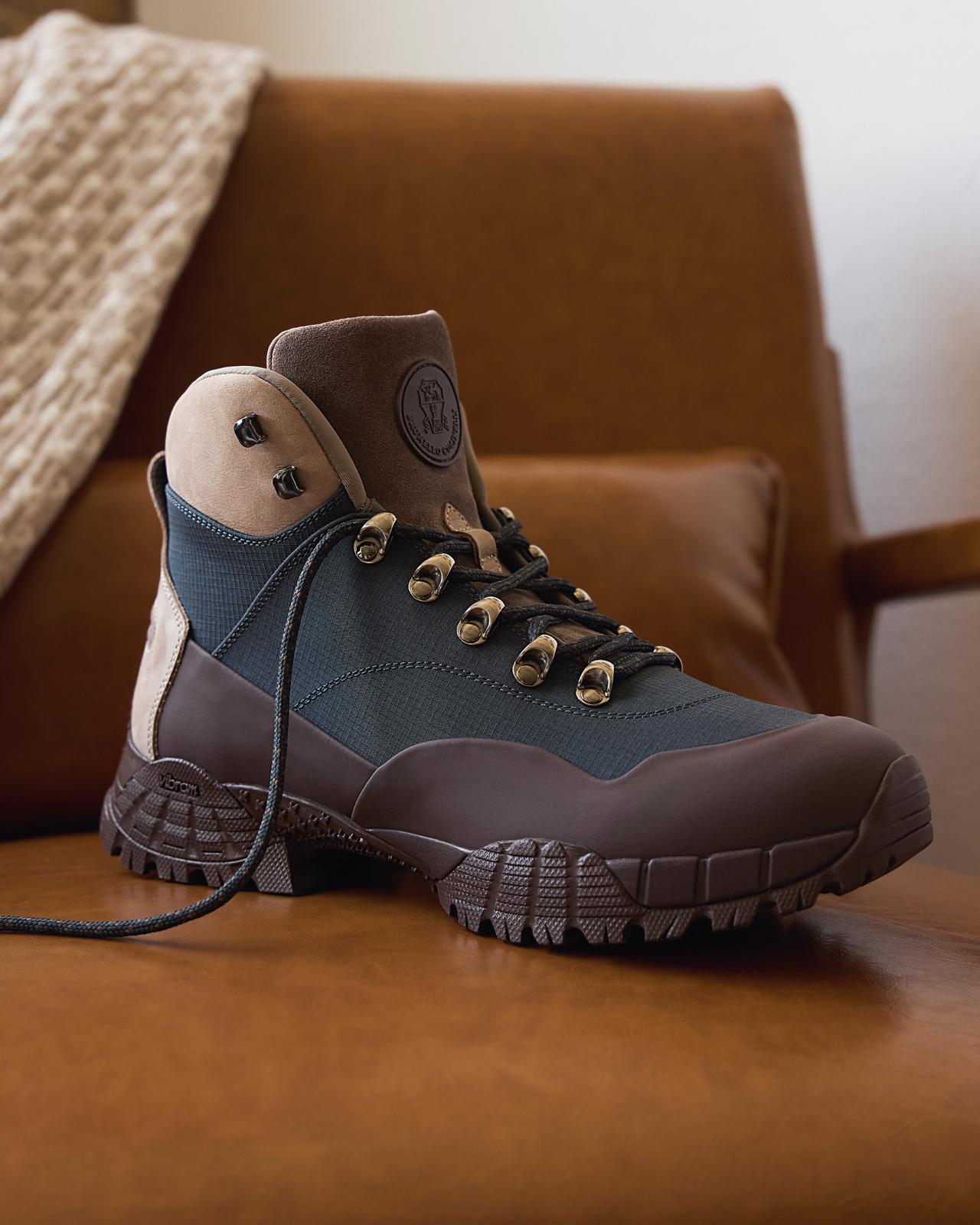 Close-up of a rugged brown and black hiking boot placed on a leather chair