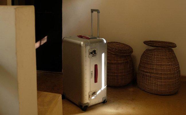 Silver suitcase with wheels and an extended handle near a doorway