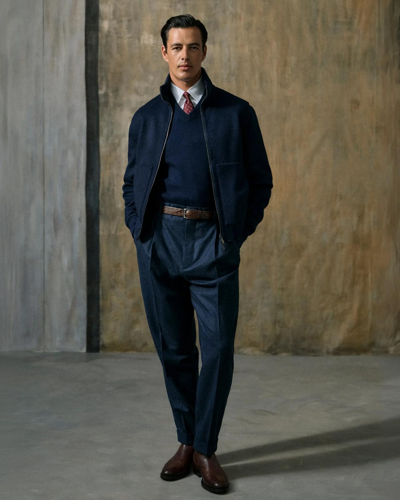 Man dressed in a navy blazer with matching sweater, white dress shirt and a tie