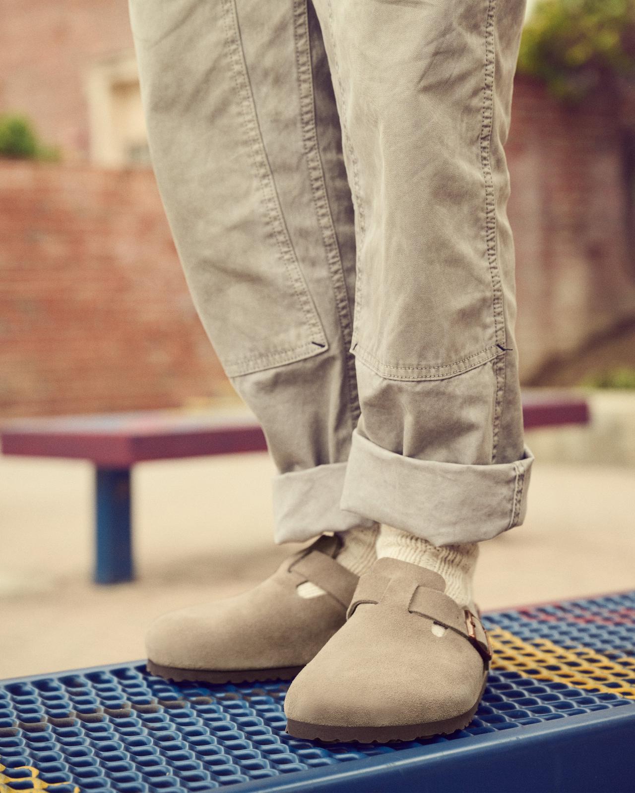 pieds masculins portant des chaussettes Birkenstock et des birkenstocks debout sur un banc à l'extérieur