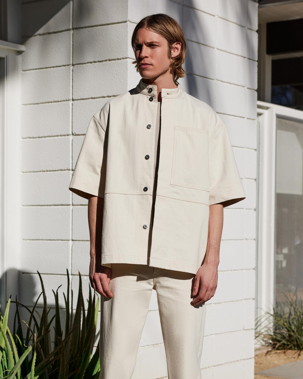 a man in a white short sleeve sport shirt and pants standing outside