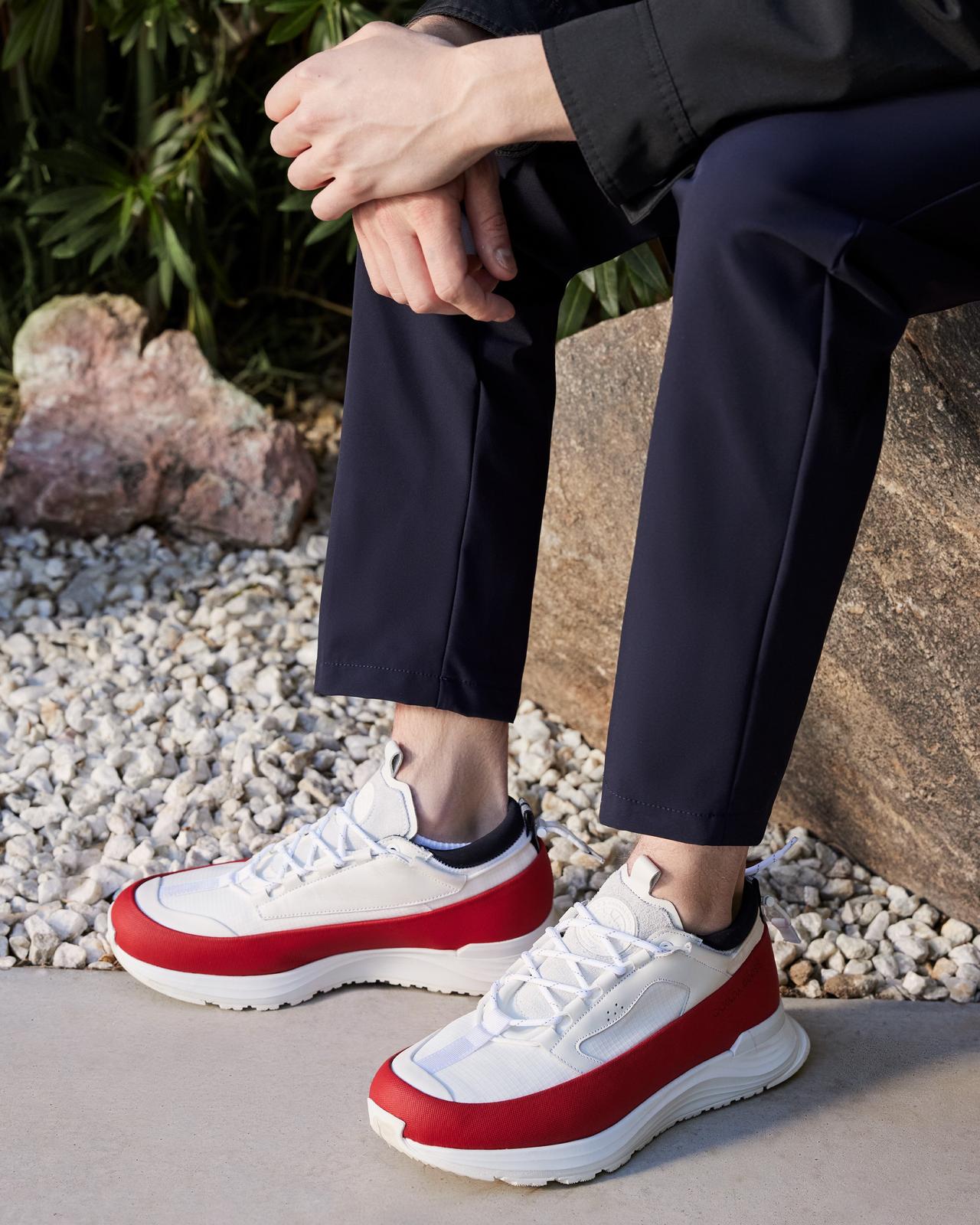 une personne assise sur un rocher portant des baskets rouges et blanches