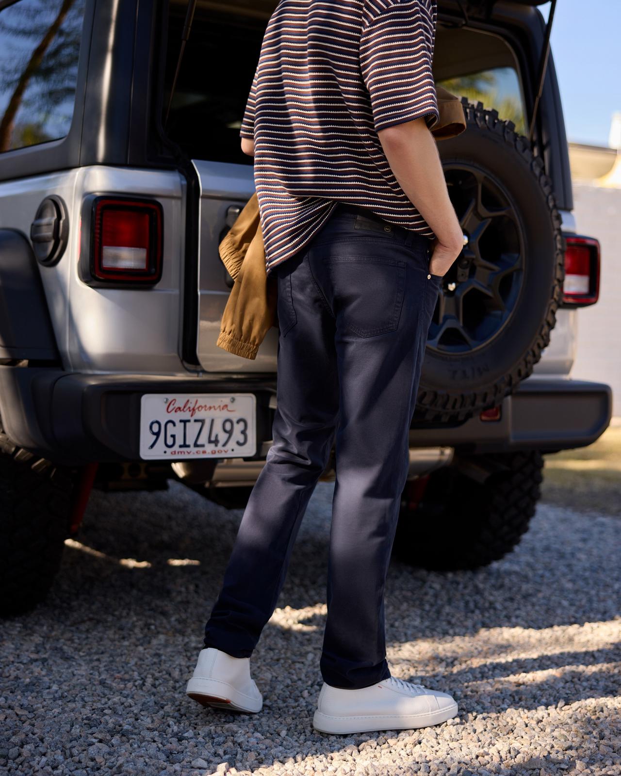 un homme debout à côté d’une jeep tenant une veste