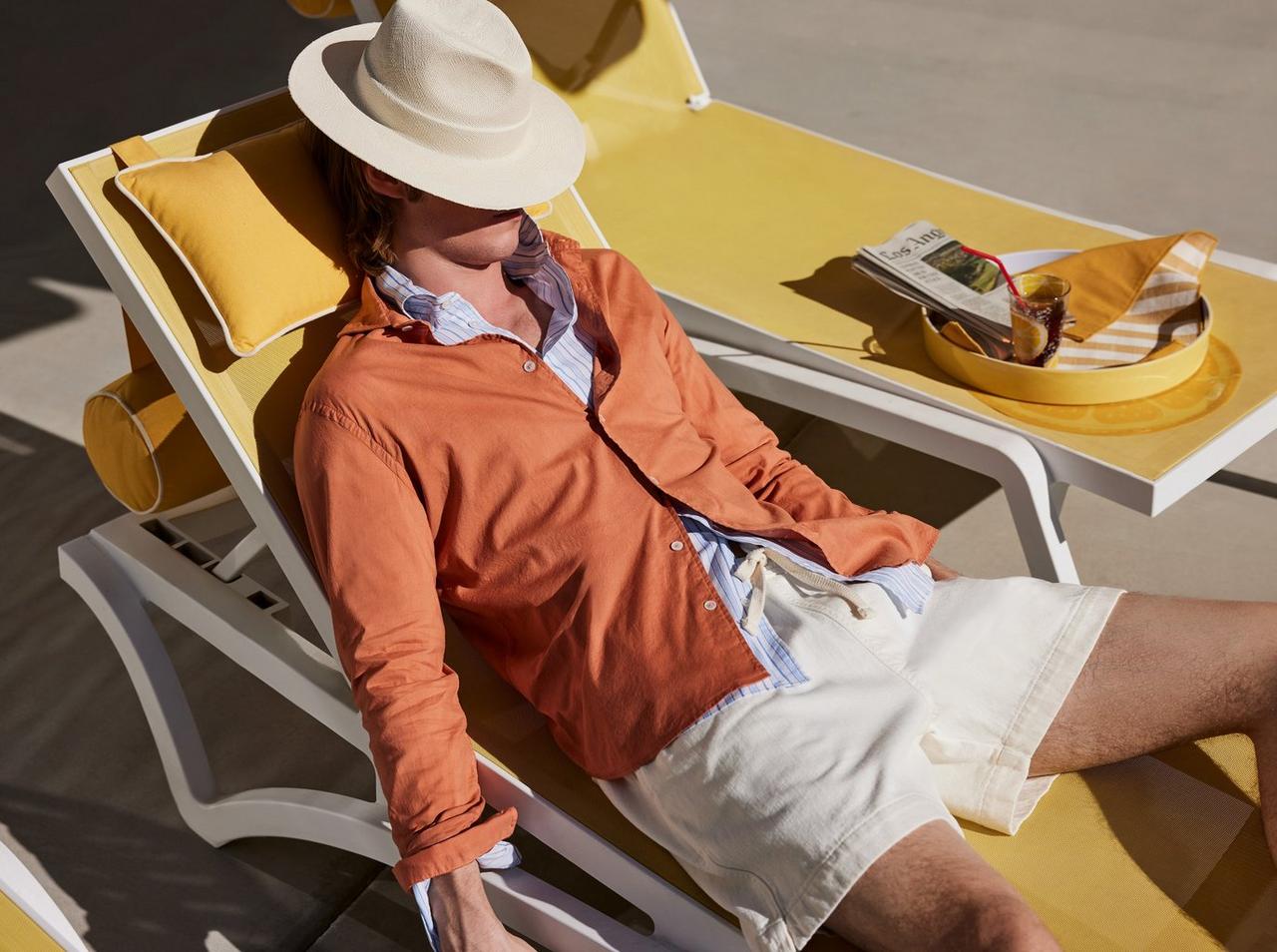 un homme au chapeau blanc assis sur une chaise longue jaune