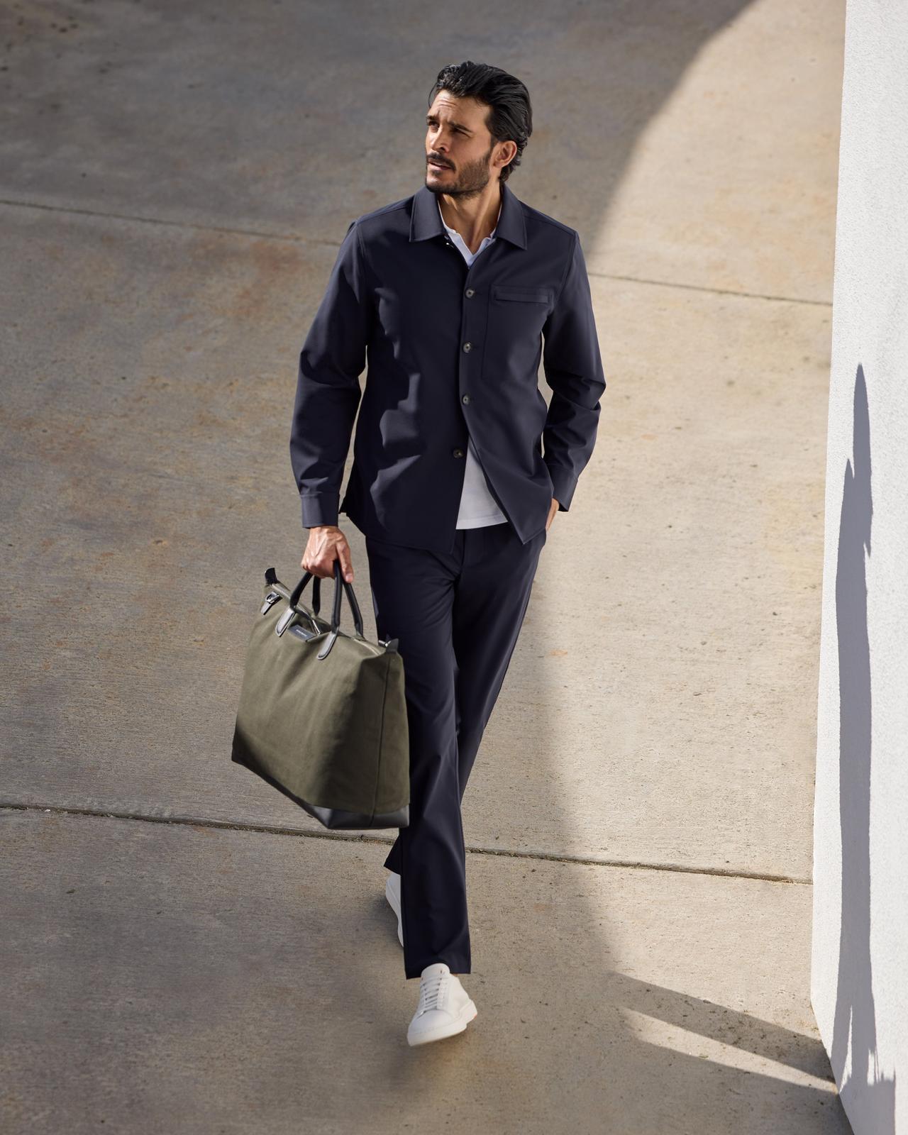 a man ina  navy set holding a bag walking