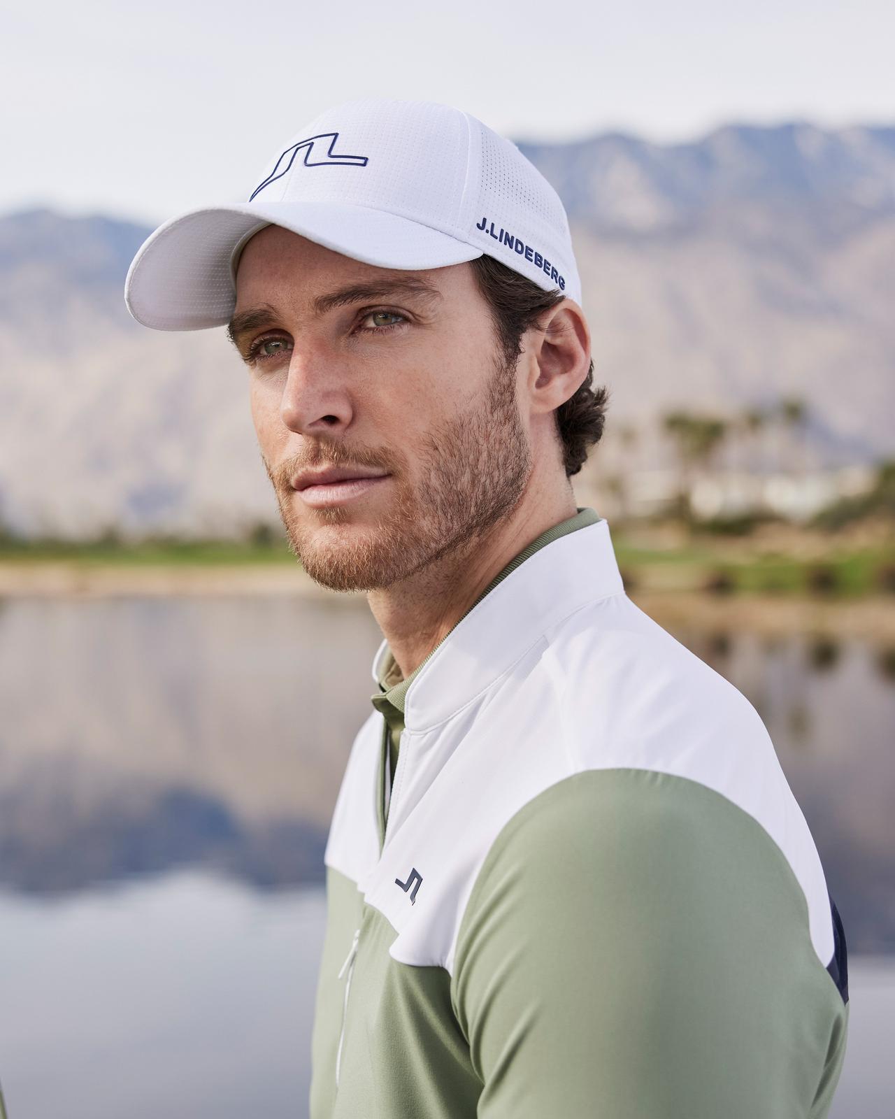 male golfer wearing a baseball cap and colour block sweater